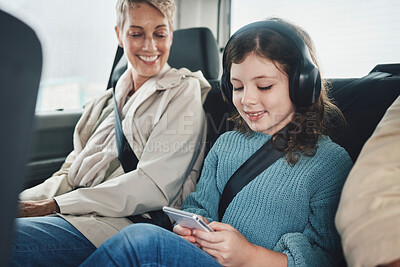 Buy stock photo Travel, driving and child with grandmother in car on a smartphone and headphones for transportation or safety belt happiness. Insurance and old woman with kid games using phone mobile app on journey