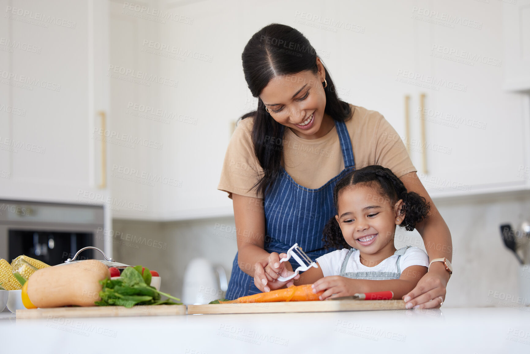 Buy stock photo Caring mother and adorable daughter cooking and bonding at home. Happy little girl helping her mother while using peeler and preparing vegetables for a healthy meal together