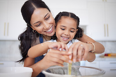 Buy stock photo Happy mother and daughter bonding, baking in a kitchen at home. Smiling single mother teacher her little daughter domestic skills against bright copy space. Kid helping her mom prepare a meal 