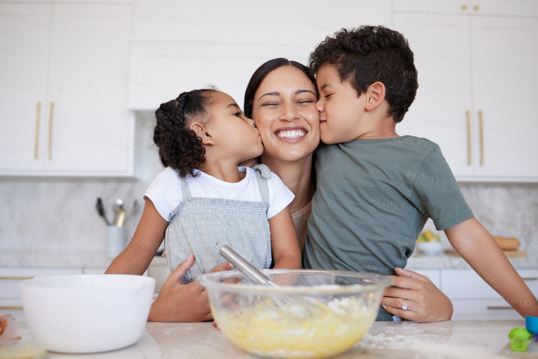 Buy stock photo Happy mother baking with cute son and daughter bonding. A young woman teaching her children to bake at home. Smiling woman getting kisses and affection while cooking with her girl and boy at home