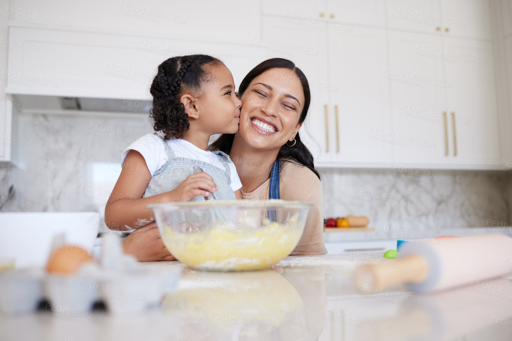 Buy stock photo Mother and daughter baking together in a home kitchen. Caring small adorable little girl kissing her single mother on the cheek. Happy woman and affectionate child bonding inside and learning to cook