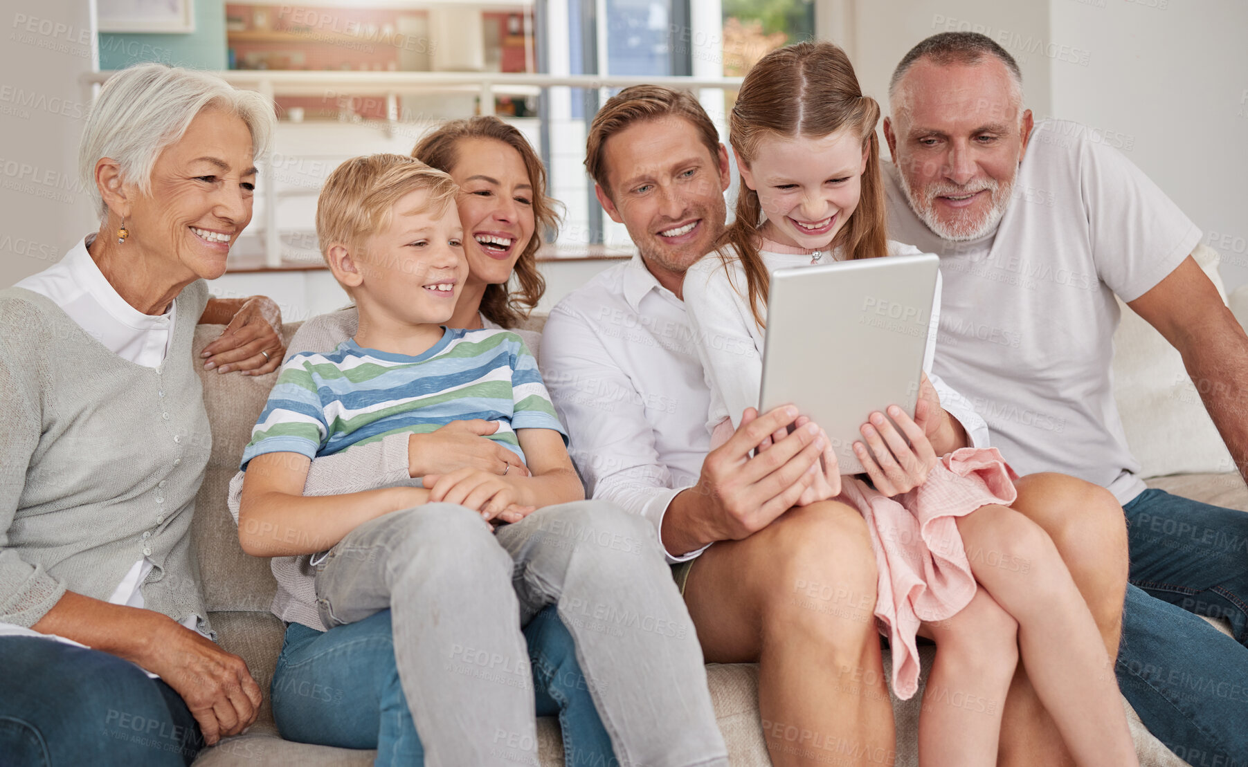 Buy stock photo Happy family using a digital tablet in the living room at home. Cute little girl and boy bonding with parents and grandparents in the lounge. Watching a movie and using technology for a video call