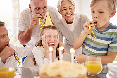 Buy stock photo Adorable little girl celebrating a birthday with her family at home. Smiling cute child feeling surprised while her brother, father and grandparents host a party for her. Happy, bonding and enjoying