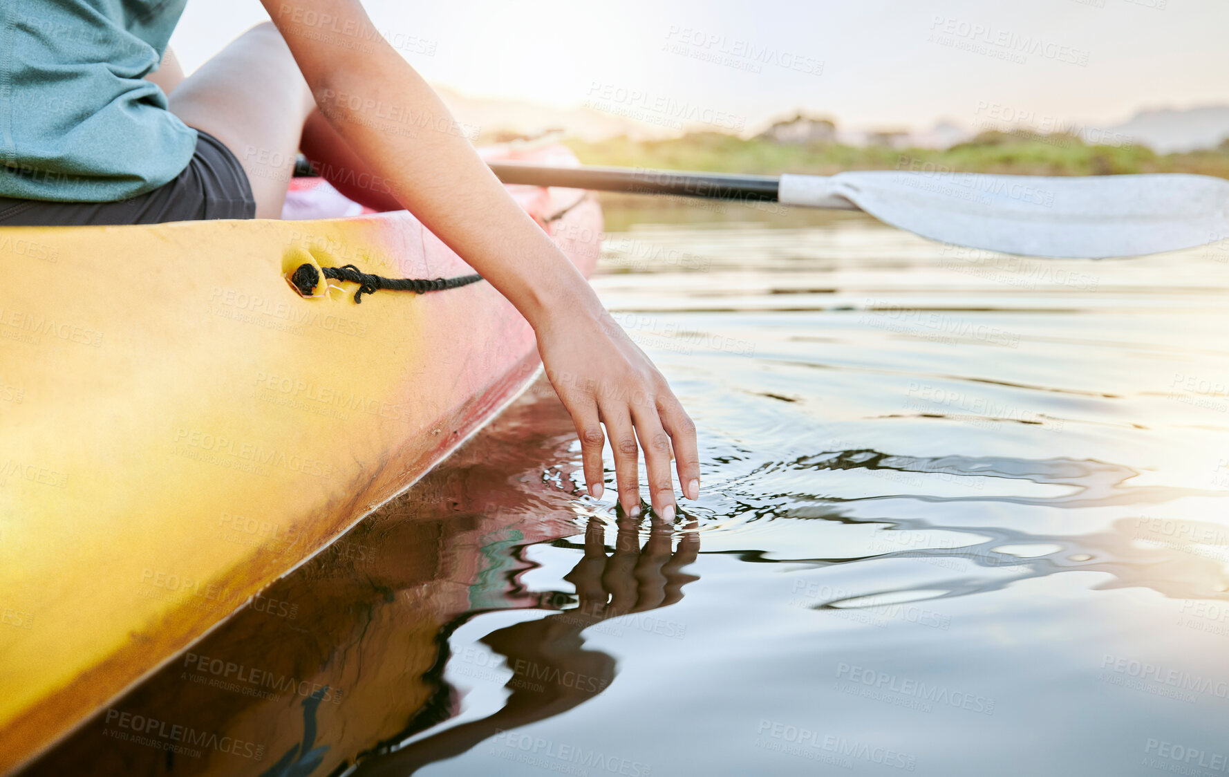 Buy stock photo Closeup of female hands kayaking and feeling lake water during the day. Active young woman enjoying water activity while on vacation in summer. Canoeing on calm sunset lake during weekend getaway