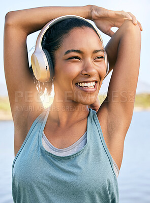 Buy stock photo One active latina woman stretching arms and triceps by pulling elbow towards spine while exercising outdoors. Female athlete doing warm up to prepare body and muscles for training workout or run while listening to music on wireless headphones