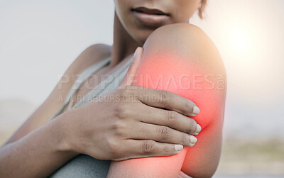 Buy stock photo Female athlete suffering from shoulder pain while exercising for fitness outside. Unknown fit sportsperson holding her arm in pain after a workout outdoors in the city. Overworking can lead to injury