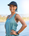 Portrait mixed race woman standing with her hands on her hips outside. Latin woman out on the lake with her arms akimbo. Happy young woman smiling outdoors while on holiday or vacation on a river