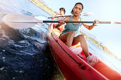 Buy stock photo Two serious friends kayaking on a lake together during summer break. Focused and stern women bonding outside in nature with water activity. Training and practicing for a kayak race during weekend