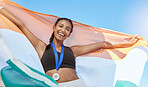 Portrait of a young fit indian female athlete cheering and holding India flag after competing in sports. Smiling fit active sporty woman feeling motivated and celebrating achieving gold medal in olympic sport. Raising national flag with pride