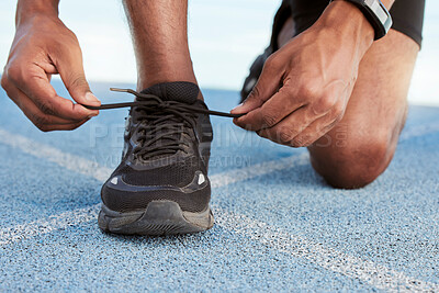 Buy stock photo Preparing for cardio training and endurance. Athlete tying shoelaces before running on a sports track, road or street. Closeup of one fit, healthy and active man getting ready to exercise and workout