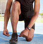 Closeup of one man tying shoelaces before run on sports track in stadium. Athlete fastening sneaker footwear for a comfortable fit and to prevent tripping while getting ready for training workout 