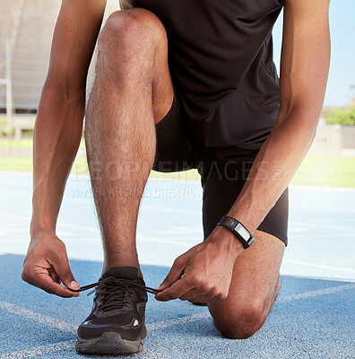 Buy stock photo Athlete preparing for a race on the track. Closeup of an athlete fastening his sneakers to prevent tripping while getting ready for cardio training and a workout on a running track