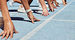 Closeup of determined group of athletes in starting position line to begin sprint or run race on sports track stadium. Hands of diverse sportspeople ready to compete in track and field olympic event