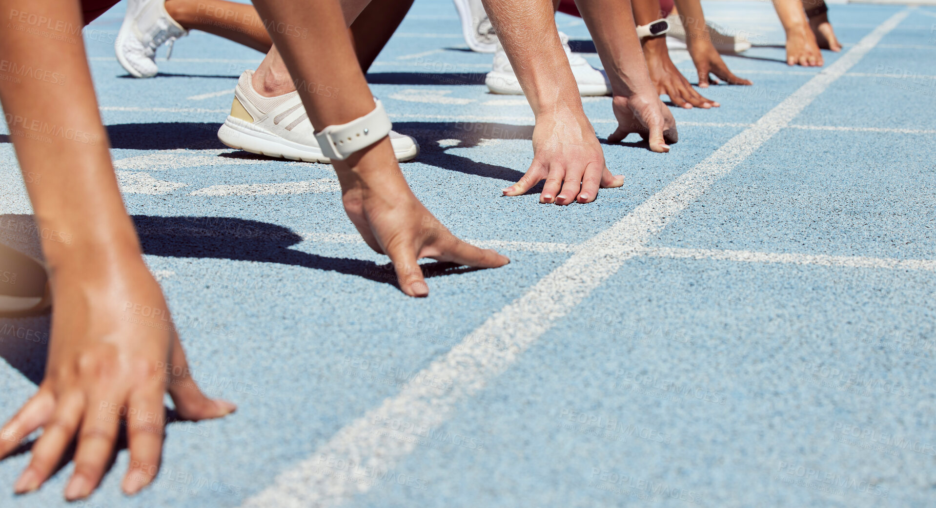 Buy stock photo Closeup of determined group of athletes in starting position line to begin sprint or run race on sports track stadium. Hands of diverse sports people ready to compete in track and field olympic event