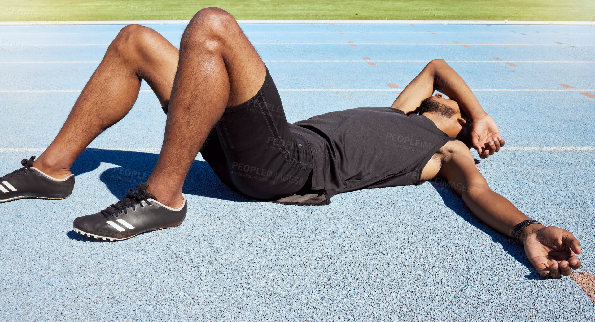 Buy stock photo Closeup of a fit active young male athlete lying exhausted flat on the track after a race and feeling tired after a sprint on a running track. Male lacking energy after a hard workout  practice run