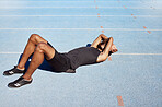 Full length track runner lying down and feeling exhausted. Active fit athlete feeling tired and suffering from heatstroke in training practice. Latino man covering his face with his arms in burnout