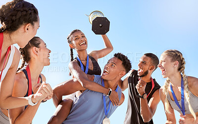 Low angle of a group of young fit diverse team of athletes celebrating their victory with a golden trophy. Team of athletes rejoicing after winning an award
