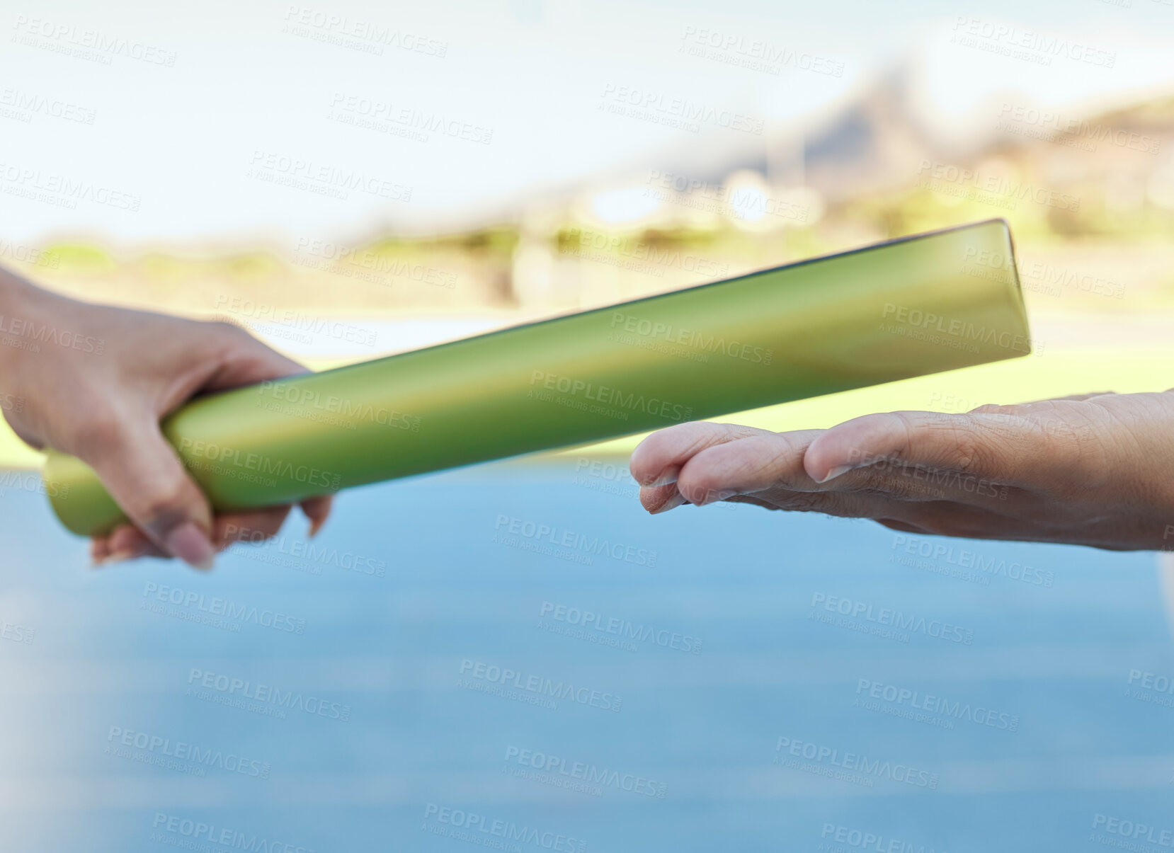 Buy stock photo Closeup of two athletes passing a baton during a relay race on a running track. Active fit athlete handing the baton over during a relay race to a team member while running in an sport competition