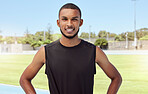 Portrait of a handsome mixed race young athlete standing alone before going for a run on a track field. Hispanic male looking confident and smiling outside