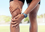 Closeup of one man holding sore knee from exercising outdoors. Uncomfortable athlete suffering with painful leg injury, fractured joint and inflamed muscles during workout. Strain due to overexertion