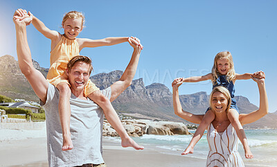 Portrait of a carefree family relaxing and bonding on the beach. Two cheerful little girls spending time with their mother and father on holiday. Mom and dad carrying their daughters on vacation