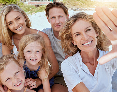Buy stock photo Portrait of a relaxed family relaxing and bonding at the beach. Two cheerful little girls spending time with their parents and grandmother on a beach vacation. Family taking  a selfie together