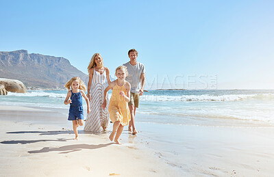 Buy stock photo Joyful young family with two children running on the beach and enjoying summer vacation. Two energetic little girls running ahead while their mother and father follow in the background