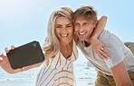 Closeup of loving young couple taking selfie with phone while enjoying a day at the beach smiling hugging and showing affection at the beach. Romantic couple showing affection while on vacation
