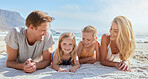 Carefree family relaxing and bonding on the beach. Two cheerful little girls spending time with their mother and father on holiday. Mom and dad admiring their daughters on vacation at the seashore