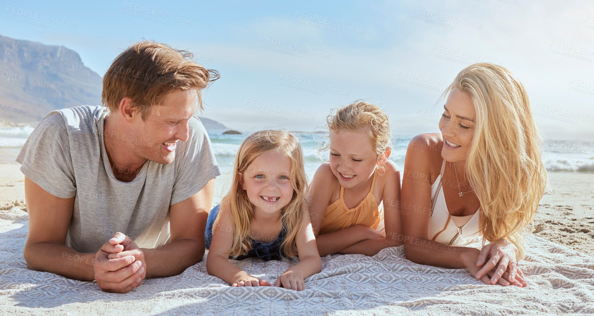 Buy stock photo Portrait of a carefree family relaxing and bonding on the beach. Cheerful little girls having fun with their mother and father on holiday. Mom and dad admiring their daughters on vacation at seashore