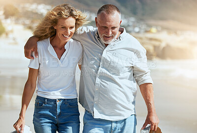 Buy stock photo Smiling mature couple embracing and walking during a beach holiday overseas. Happy husband and wife enjoying free time and break. Man and woman bonding and holding each other on romantic summer date