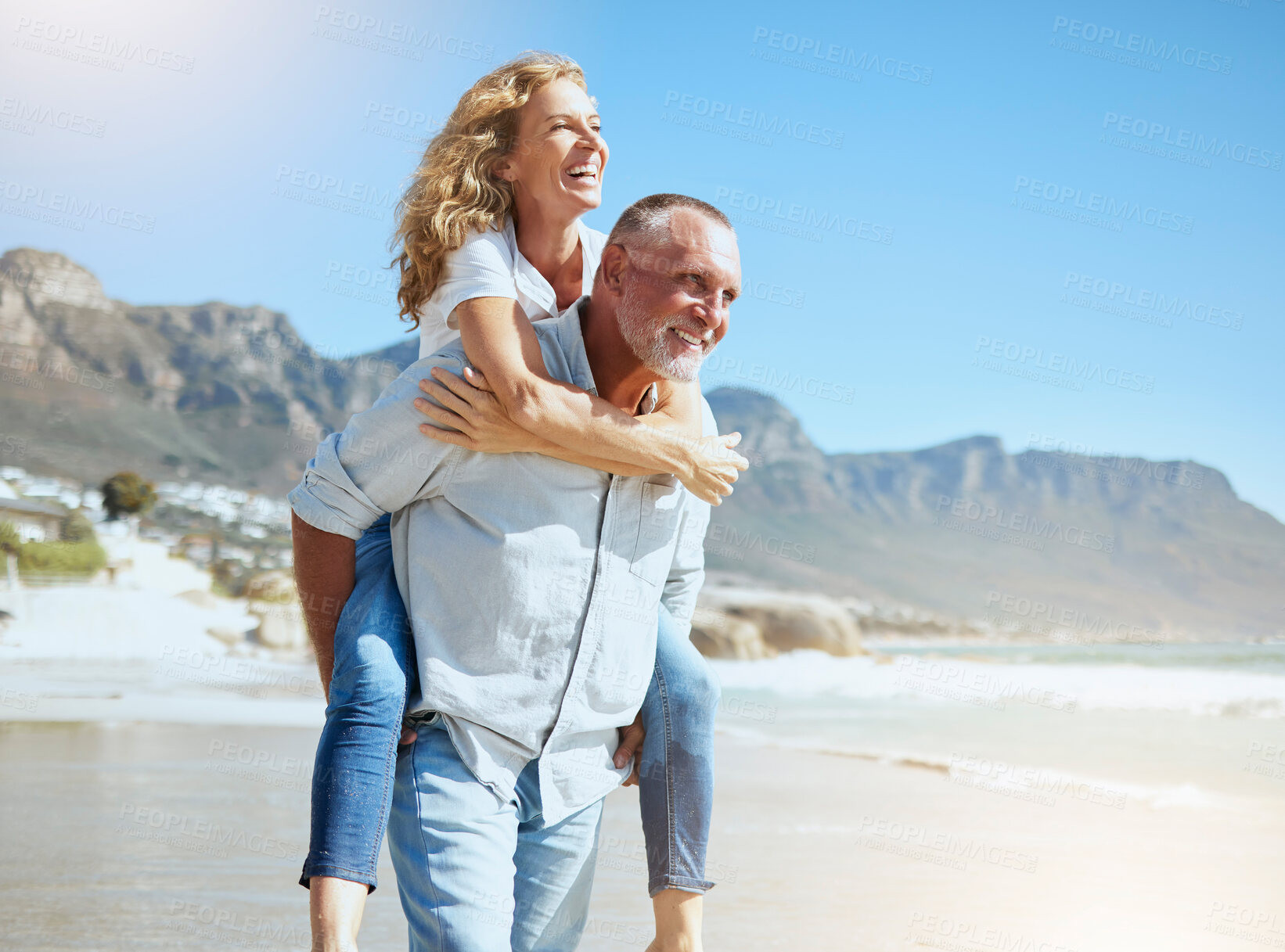 Buy stock photo Happy mature couple enjoying vacation by the beach. Active senior husband giving his wife a piggyback ride while enjoying a sunny day outdoors. Energetic man and woman having fun while on holiday