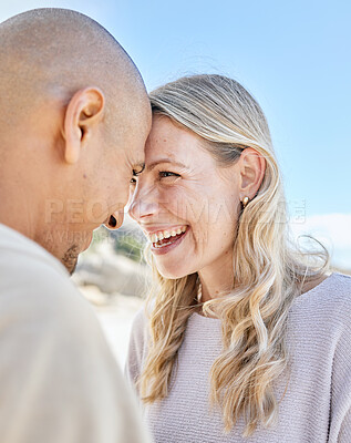 Closeup of a mature interracial couple spending time together at the beach standing close to each other and smiling affectionately