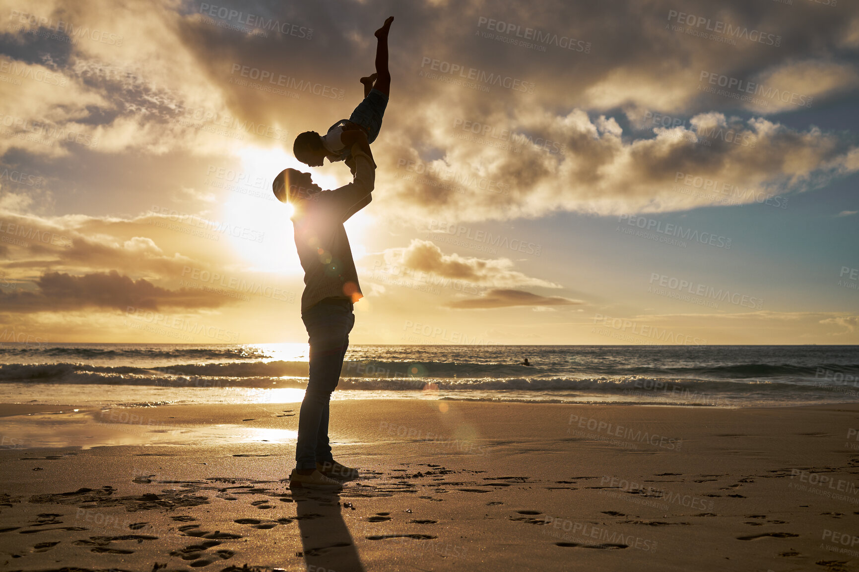 Buy stock photo Little girl playing and bonding with her dad on vacation. Silhouette of a loving father holding up his little child on the beach against golden sky. Parent lifting his daughter against sunset sky. 