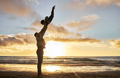 Silhouette of a carefree father holding up his child on the beach. Parent spending time with their daughter while on holiday. Happy little girl playing and bonding with her dad on vacation
