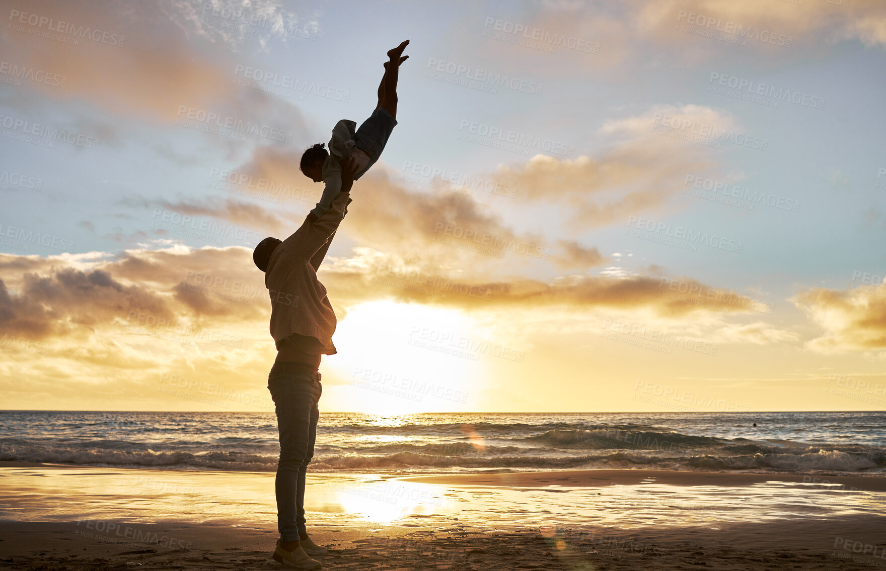 Buy stock photo Silhouette of a carefree father holding up his child on the beach. Parent spending time with their daughter while on holiday. Happy little girl playing and bonding with her dad on vacation