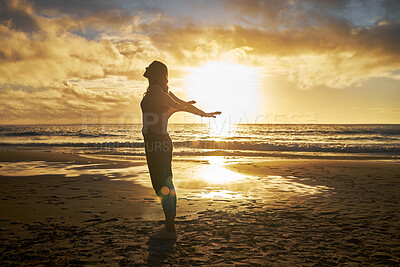Buy stock photo Rear View of a silhouette woman stretching with her arms out at the beach during sunset. Calm relaxed female feeling freed and enjoying a golden sunset out in nature. Golden sunset during dusk 