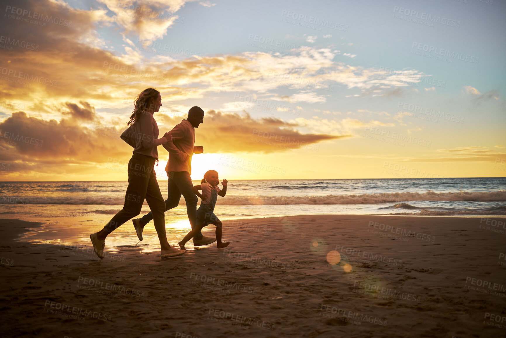Buy stock photo Silhouette of a carefree family running and having fun together during sunset on the beach. Parents spend time with their daughters on holiday. Little girl playing with her parents while on vacation