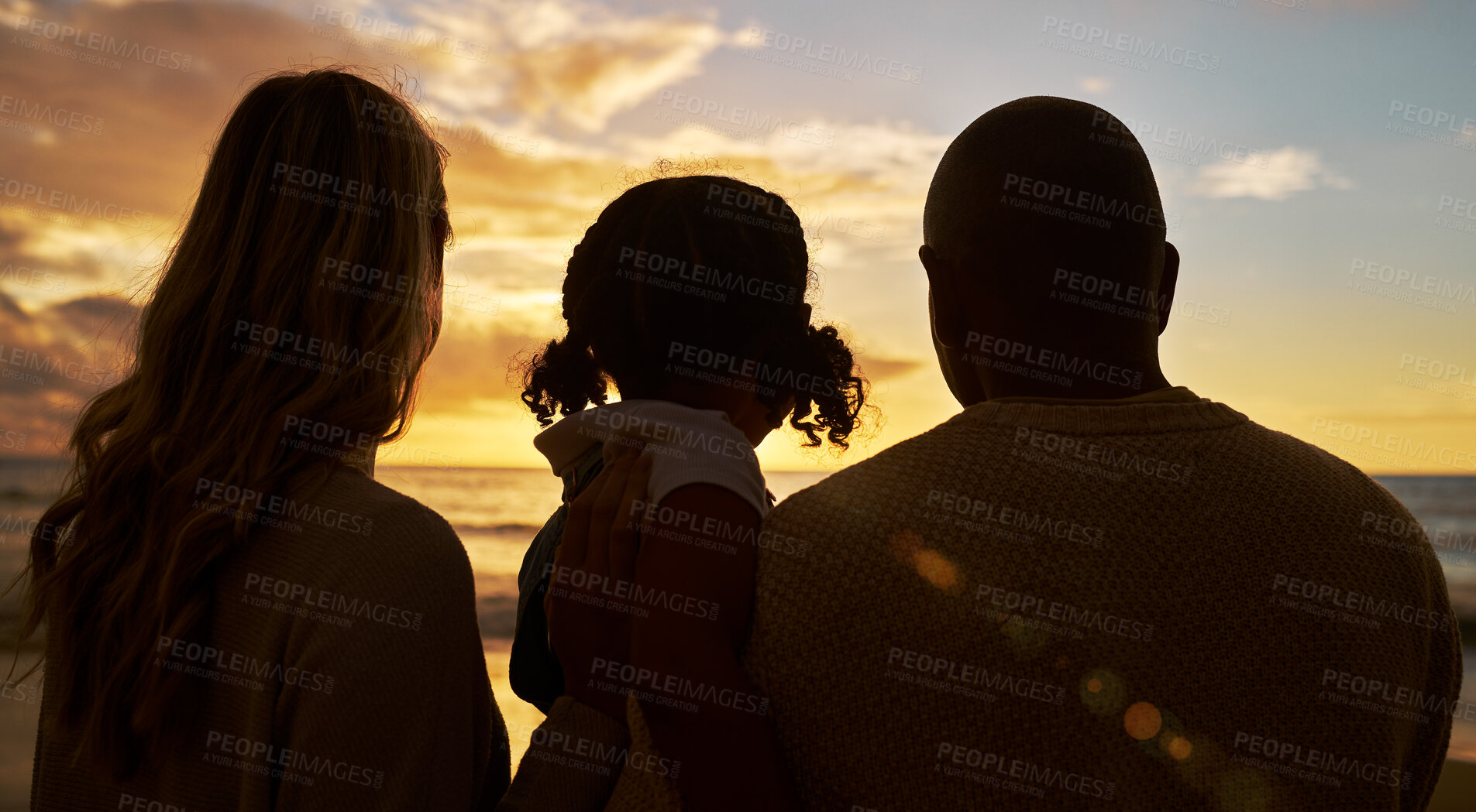 Buy stock photo Silhouette closeup of happy family with one child on the beach looking at view at sunset. Two parents and daughter admiring golden sky and calm sea while enjoying their vacation and spending time