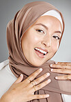 Studio portrait of beautiful muslim woman isolated against a grey background. Young woman wearing a hijab or headscarf showing traditional arab modesty while smiling and looking at camera