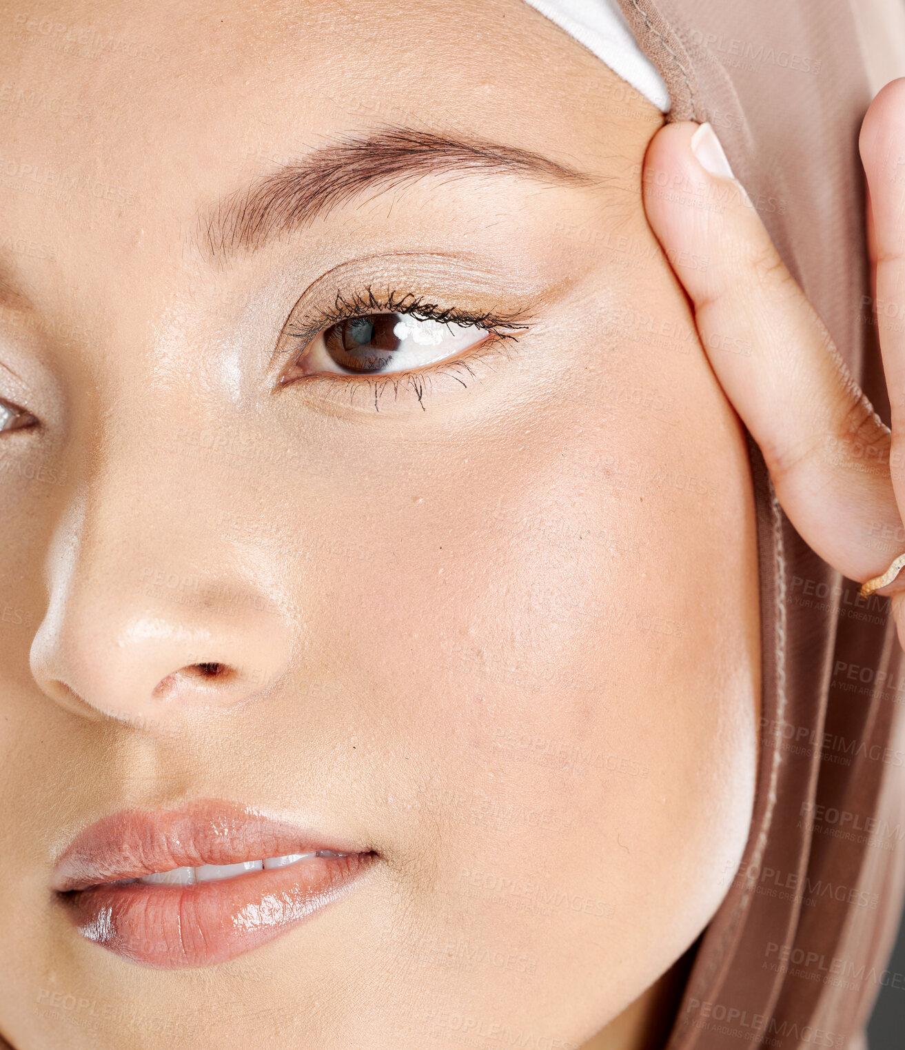 Buy stock photo Face of a beautiful Muslim woman wearing a brown headscarf and lifting the skin around her eyes. Headshot of hijab lady contemplating eyelift surgery for a more youthful and wrinkle free appearance 