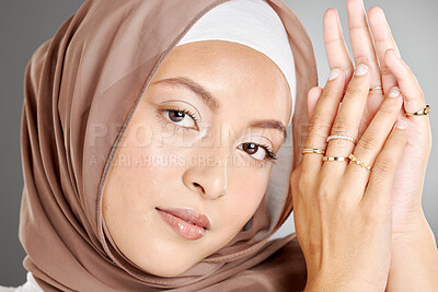 Buy stock photo Studio portrait of beautiful muslim woman wearing a brown headscarf and showing multiple rings on her hands. Female wearing hijab and glowing makeup with trendy jewelry showing off her modest beauty