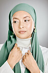 Closeup of a beautiful muslim woman posing in a studio with a green hijab. Headshot of a stunning confident arab model isolated against a grey background. Zoomed in on young fashionable middle eastern