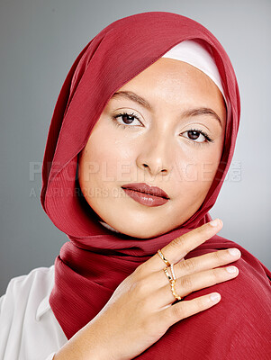 Buy stock photo Portrait of stylish muslim woman with makeup and gold rings isolated against grey background. Edgy young hijab lady feeling confident in her red scarf and trendy costume jewelry. Modesty and beauty