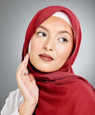 Buy stock photo A glowing beautiful muslim woman isolated against grey copyspace background. Young woman wearing a hijab or headscarf showing her eyelash extensions while daydreaming, touching her flawless skin