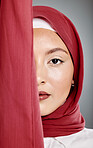 Closeup portrait of beautiful muslim woman wearing a hijab, posing in studio. Half headshot of stunning confident arab model isolated against grey background. Zoomed in on fashionable middle eastern