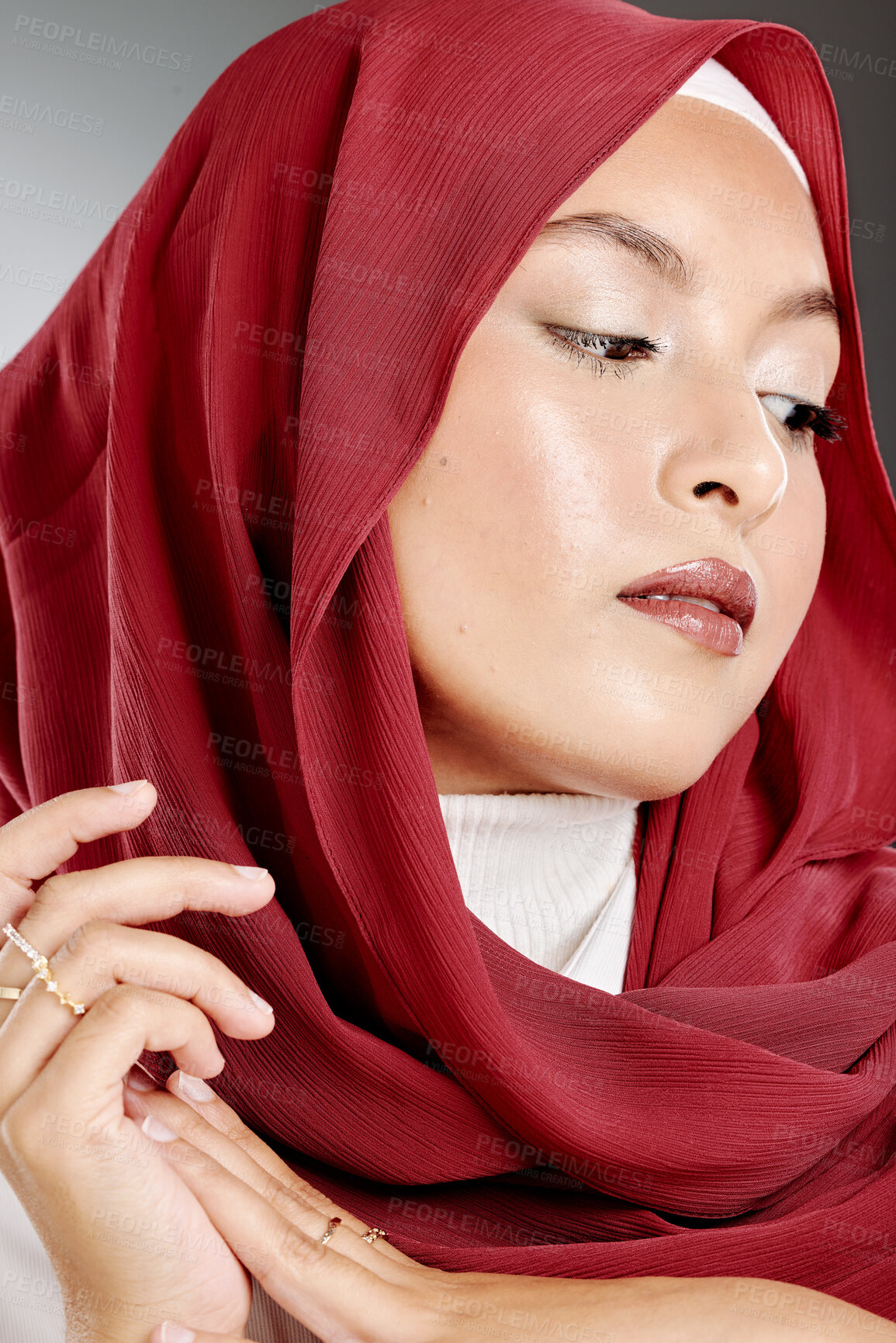 Buy stock photo Elegant muslim woman posing in a studio wearing a hijab. Headshot of a gorgeous and confident arab model standing against a grey background. Fashionable woman wearing a headscarf