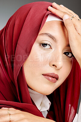 Portrait of a muslim woman posing in a studio wearing a hijab. Headshot of a stunning confident arab model standing against a grey background. Fashionable woman wearing a headscarf