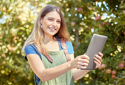 Buy stock photo A female apple farmer standing and using a digital tablet while checking her plants. Smiling woman using technology to prepare for harvest on her farm. Monitoring plant growth and agriculture