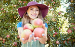 Portrait of one happy young woman holding freshly picked red from trees on sustainable orchard farmland outside on sunny day. Farmer harvesting juicy nutritious organic fruit in season ready to eat